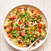 potato and vegetable salad in pink bowl with spoon