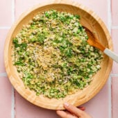 hand tossing pasta salad in wooden bowl