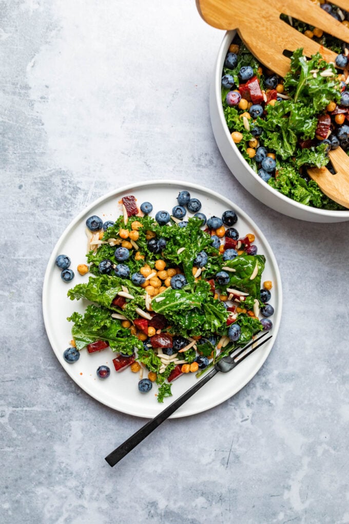 kale and blueberry salad on white plate with fork