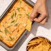 hand dipping chip into buffalo dip