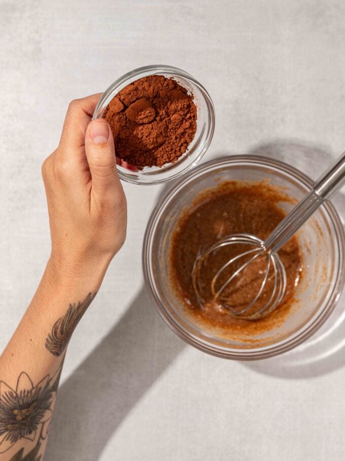 hand pouring cocoa into batter