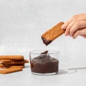 hand dipping cookie into chocolate dip