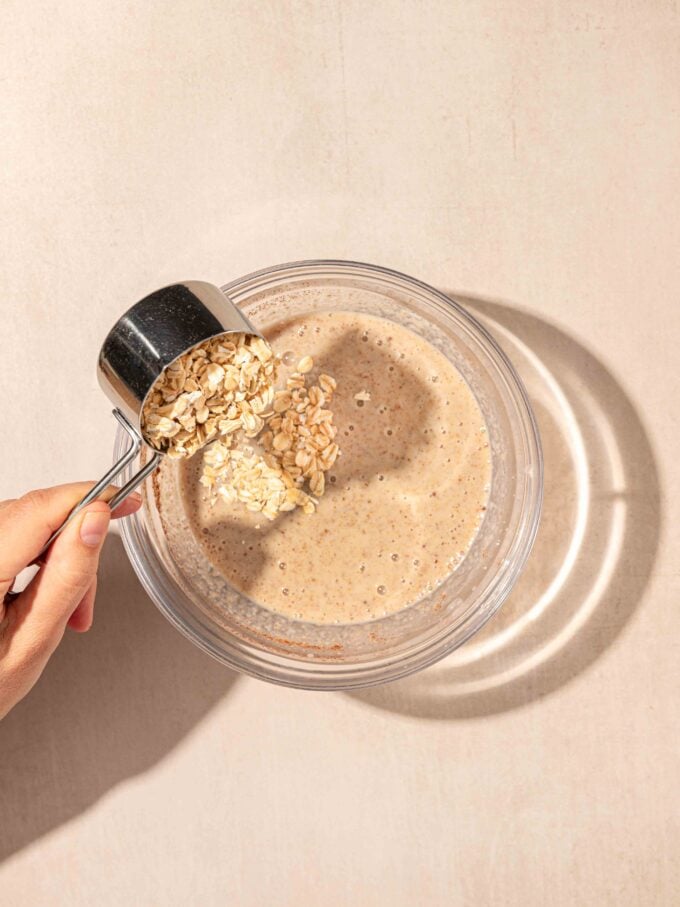 hand adding oats to bowl of milk