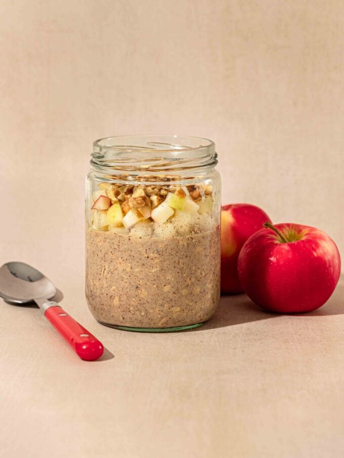 jar of apple pie overnight oats with spoon and apples