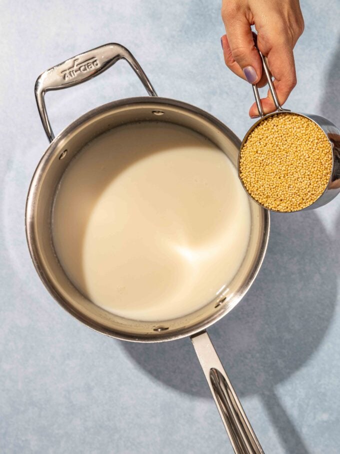 hand pouring millet into pot