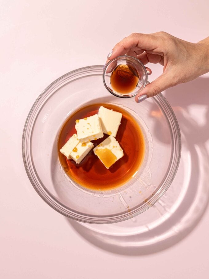 hand pouring vanilla into bowl