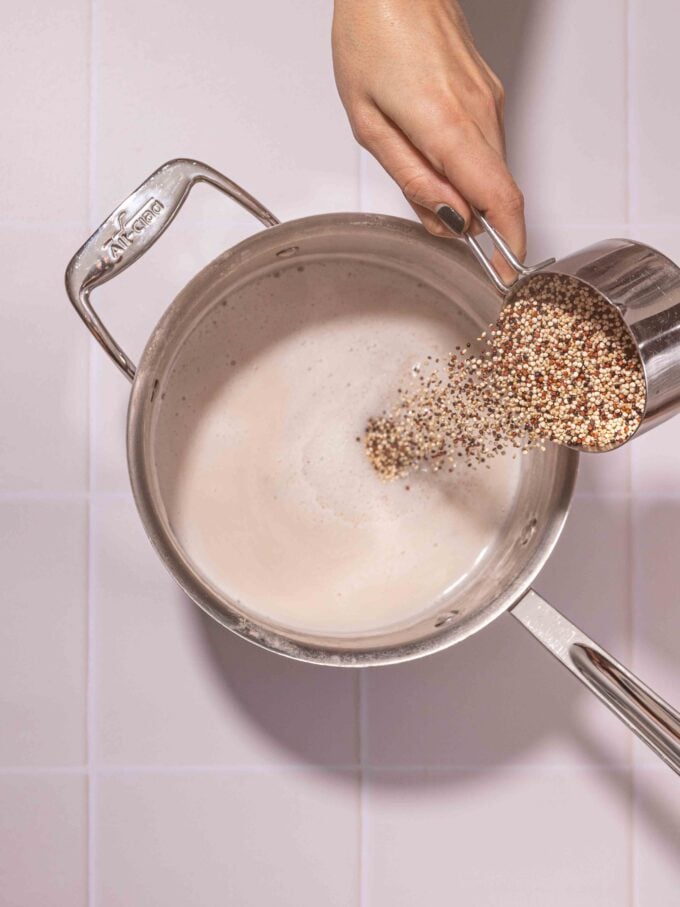 hand pouring quinoa into pot