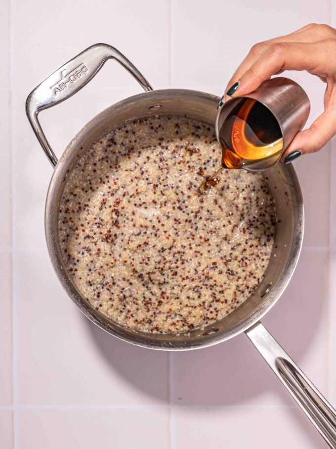 hand pouring maple syrup into quinoa