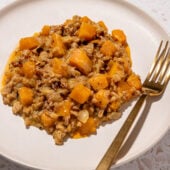 butternut squash vegan farro risotto on white plate with gold fork