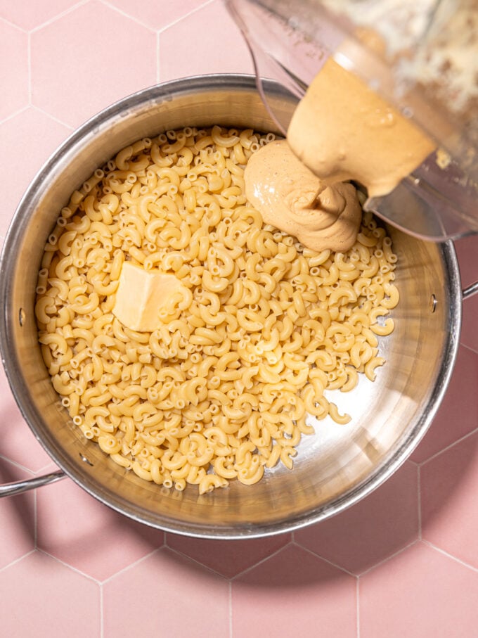 pouring mac and cheese sauce on pasta