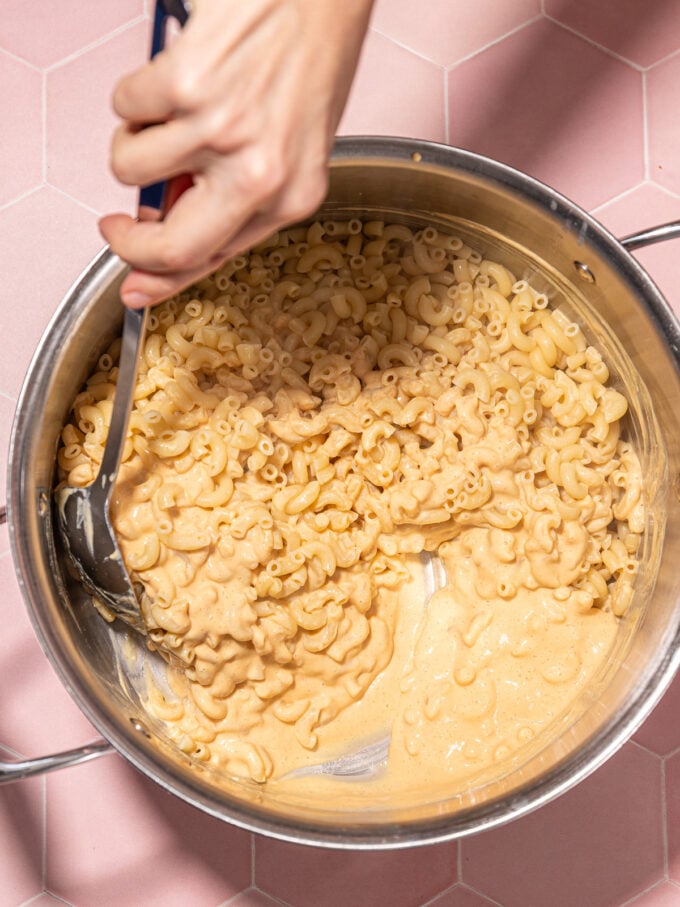 hand stirring vegan mac and cheese in pot