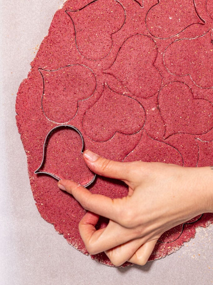 hand cutting pink heart cookies