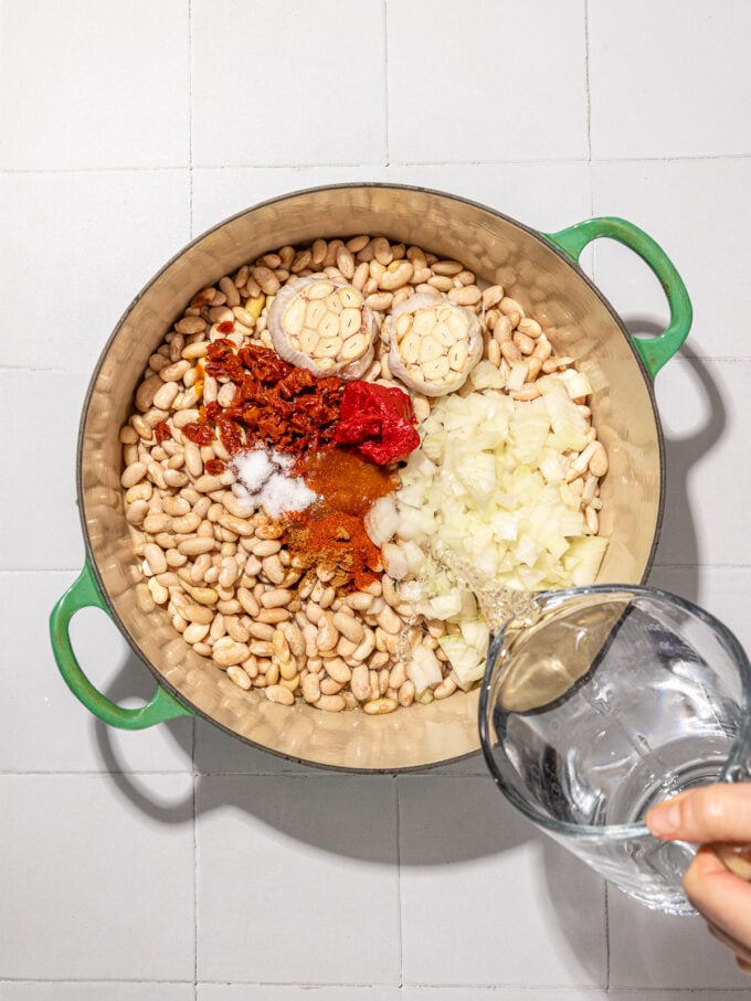 hand pouring water into pot of white beans