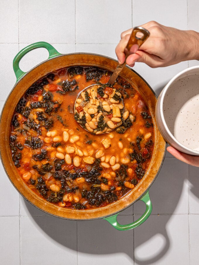 hand ladling brothy beans into bowl