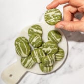 hand holding matcha cookies drizzled with white chocolate