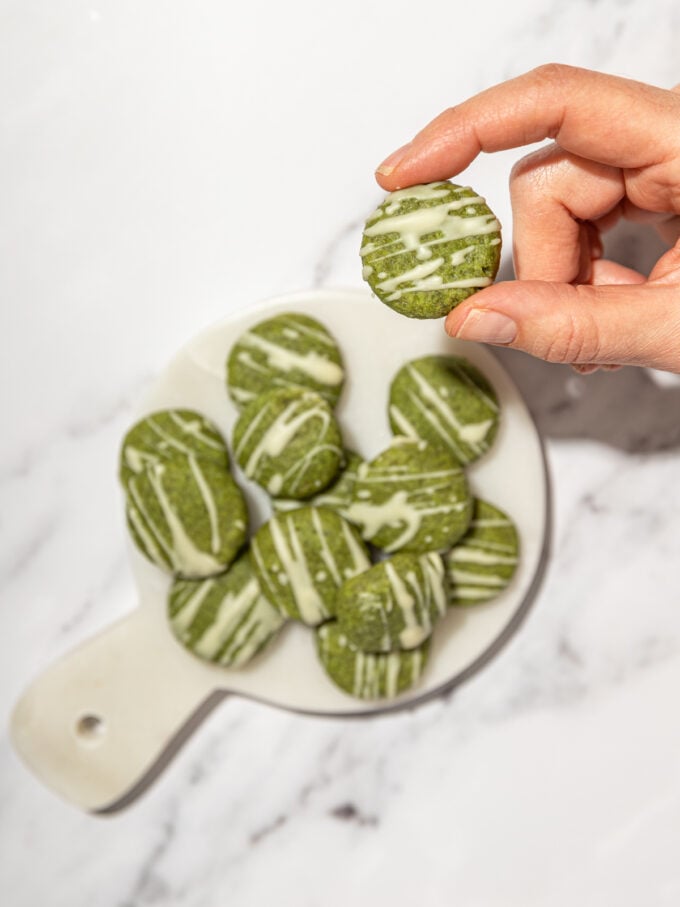 hand holding matcha cookies drizzled with white chocolate