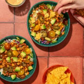 hand crushing tortilla chips on vegan taco salad