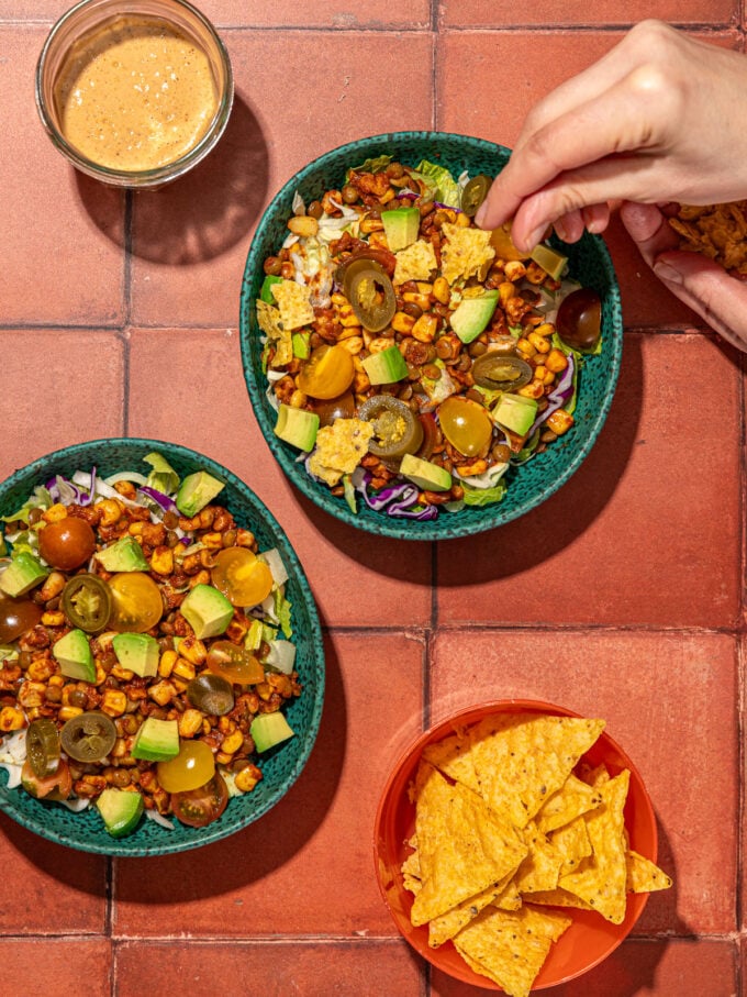 hand crushing tortilla chips on vegan taco salad