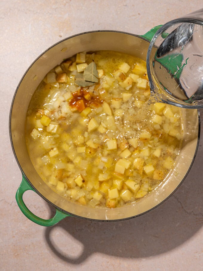 pouring water into pot with potatoes