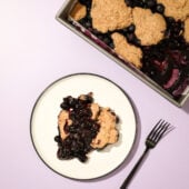 blueberry cobbler on white plate with black fork