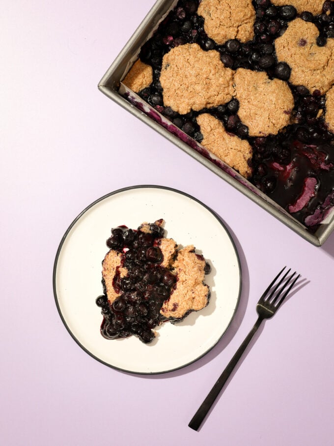 blueberry cobbler on white plate with black fork