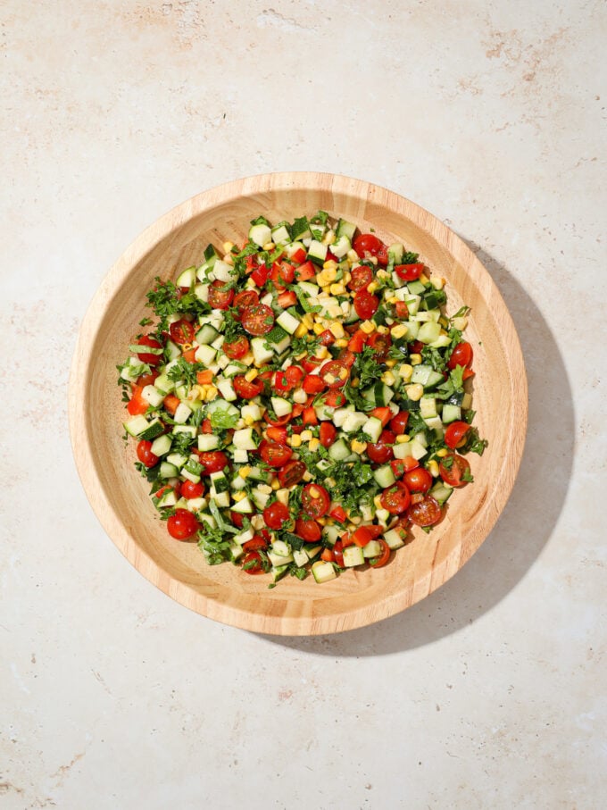 chopped summer vegetable salad in wooden bowl