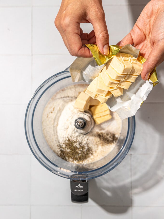 hand adding butter to food processor