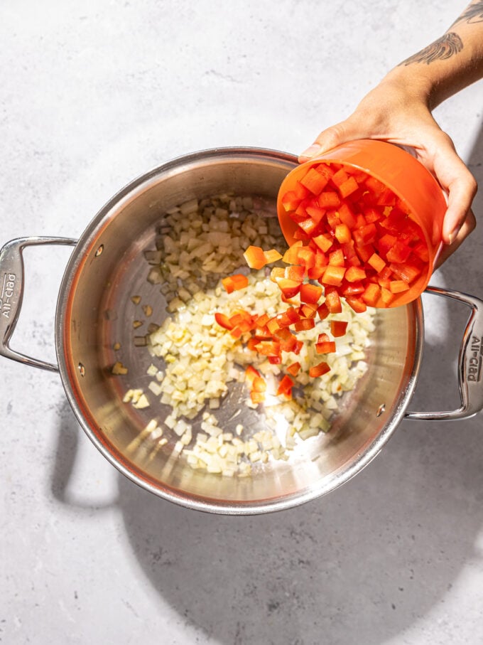 hand pouring red peppers into pot