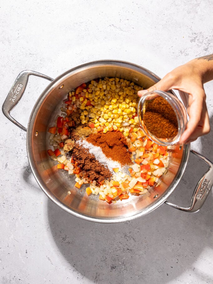 hand pouring chili powder into pot