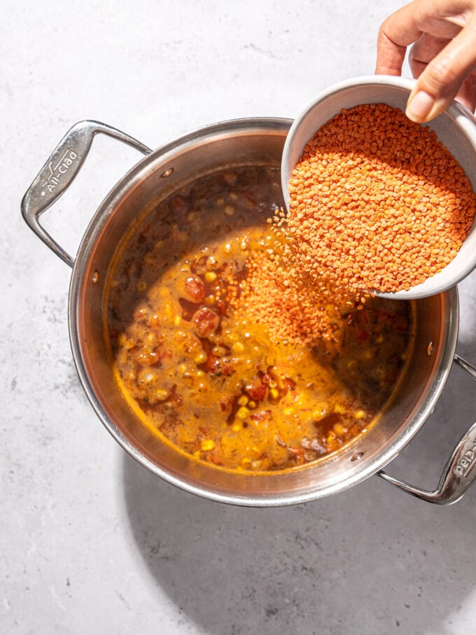 hand pouring red lentils into pot