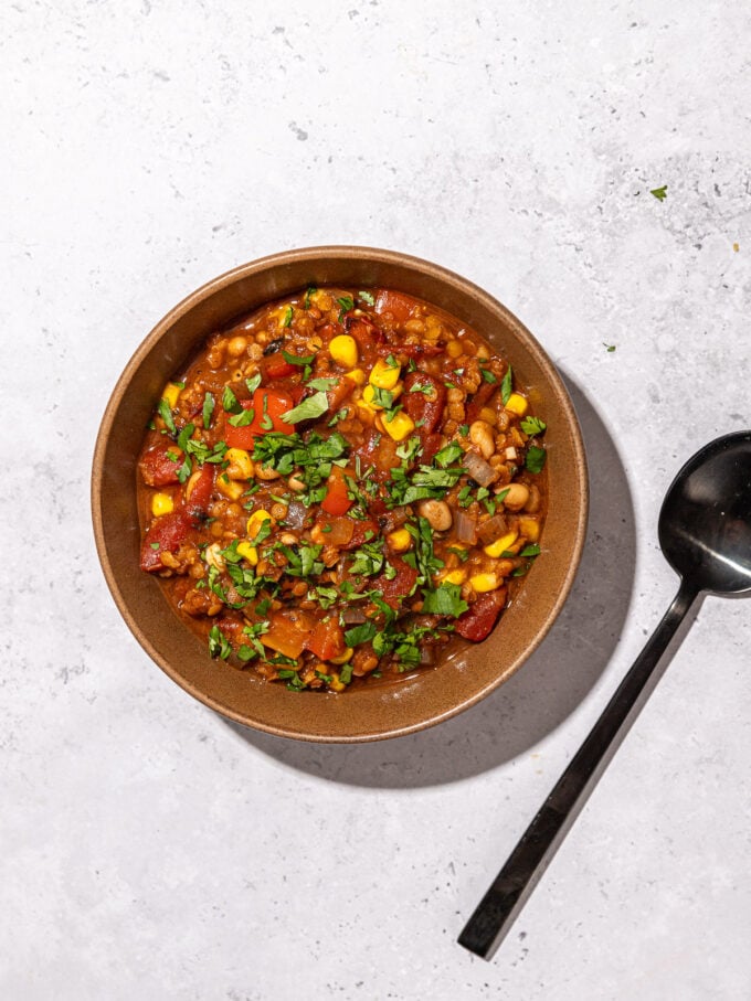 red lentil chili in brown bowl with black spoon