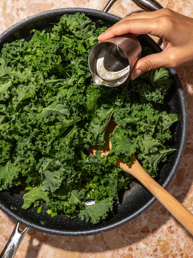 hand pouring water into pan of kale