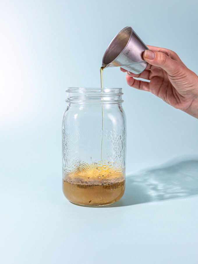 hand pouring oil into mason jar