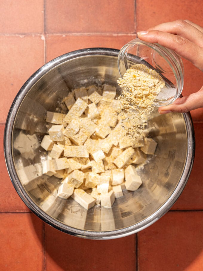 hand shaking cornstarch over tofu