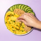 hand scooping red lentil dip with cracker